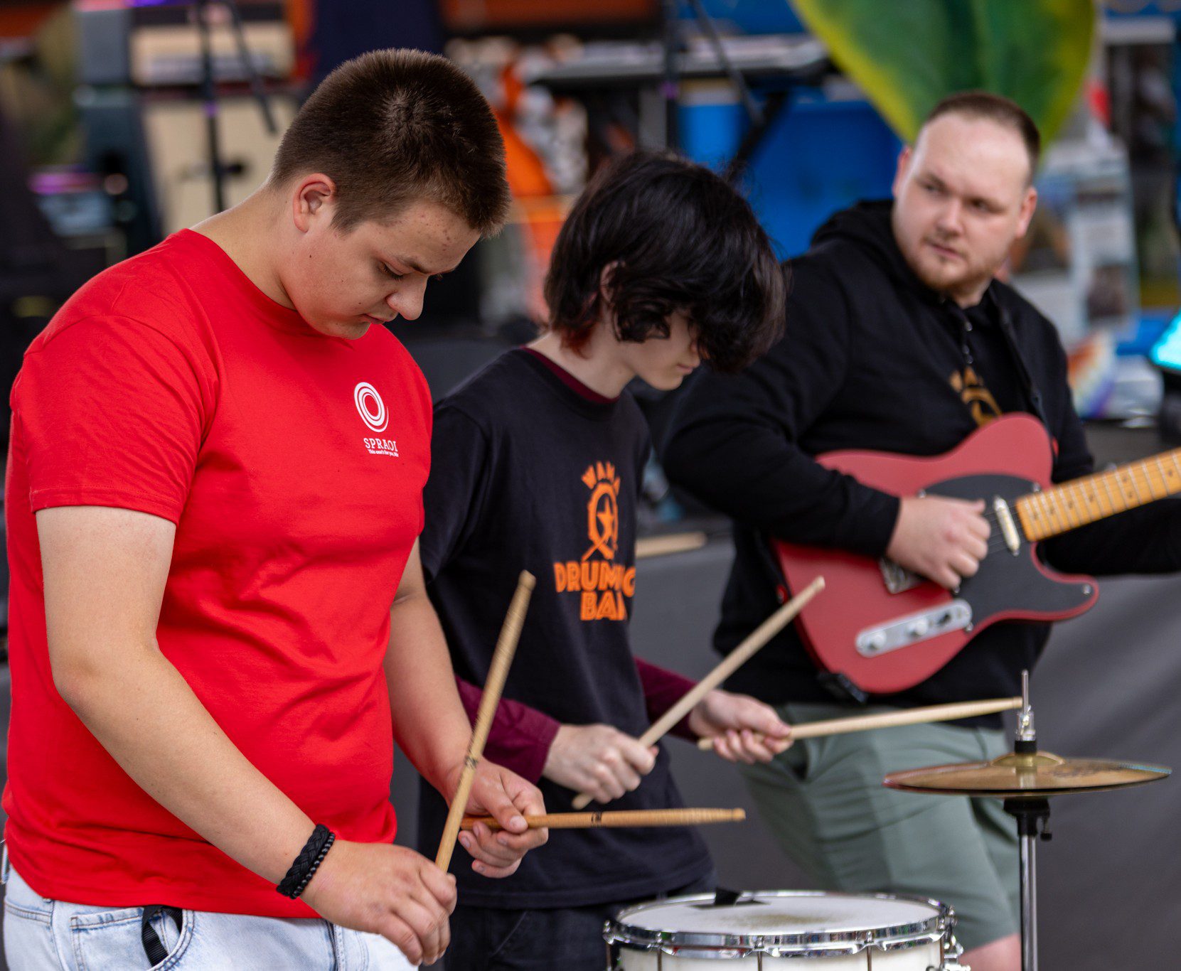 Two boy banging drums and one man playing the electric guitar at SPRAOI