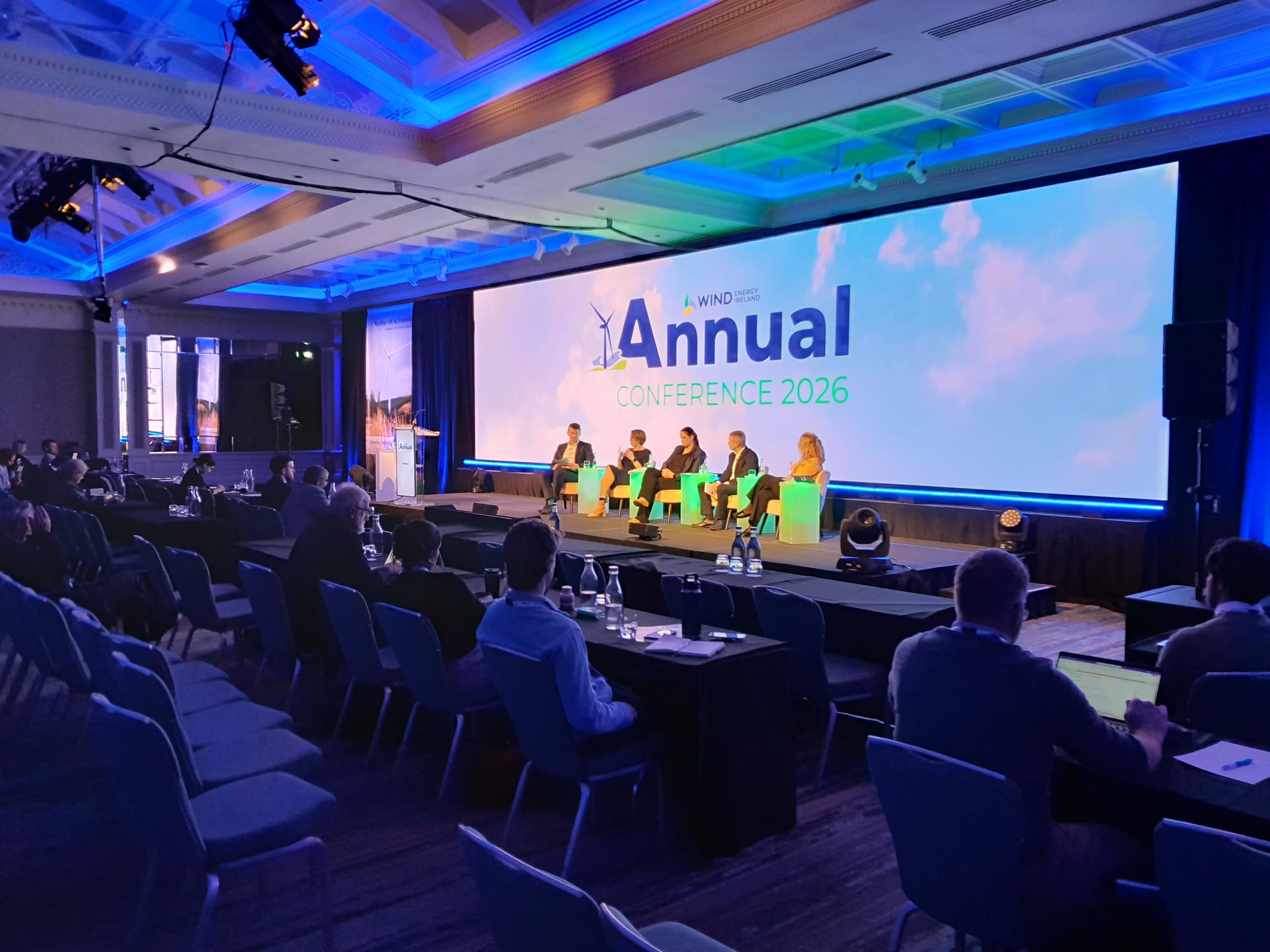 Dark room with view of audience and presenter at a podium.